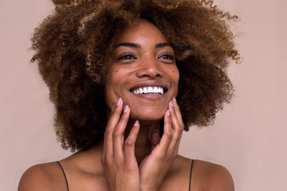 Beautiful smiling woman with healthy hair rich in biotin.