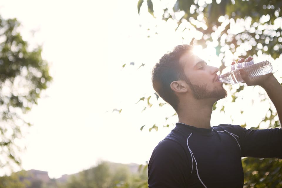 man hydrates and replenishes with water during exercise run